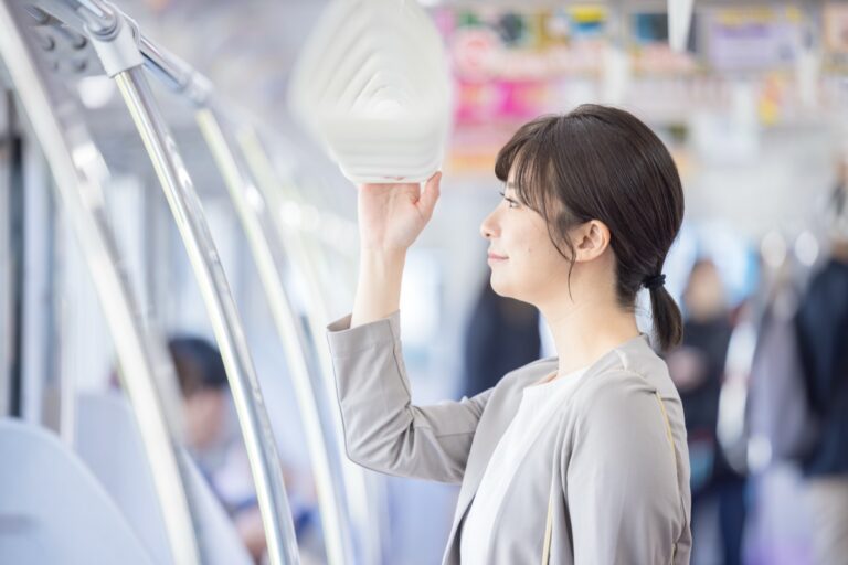 電車でつり革につかまって立つ女性