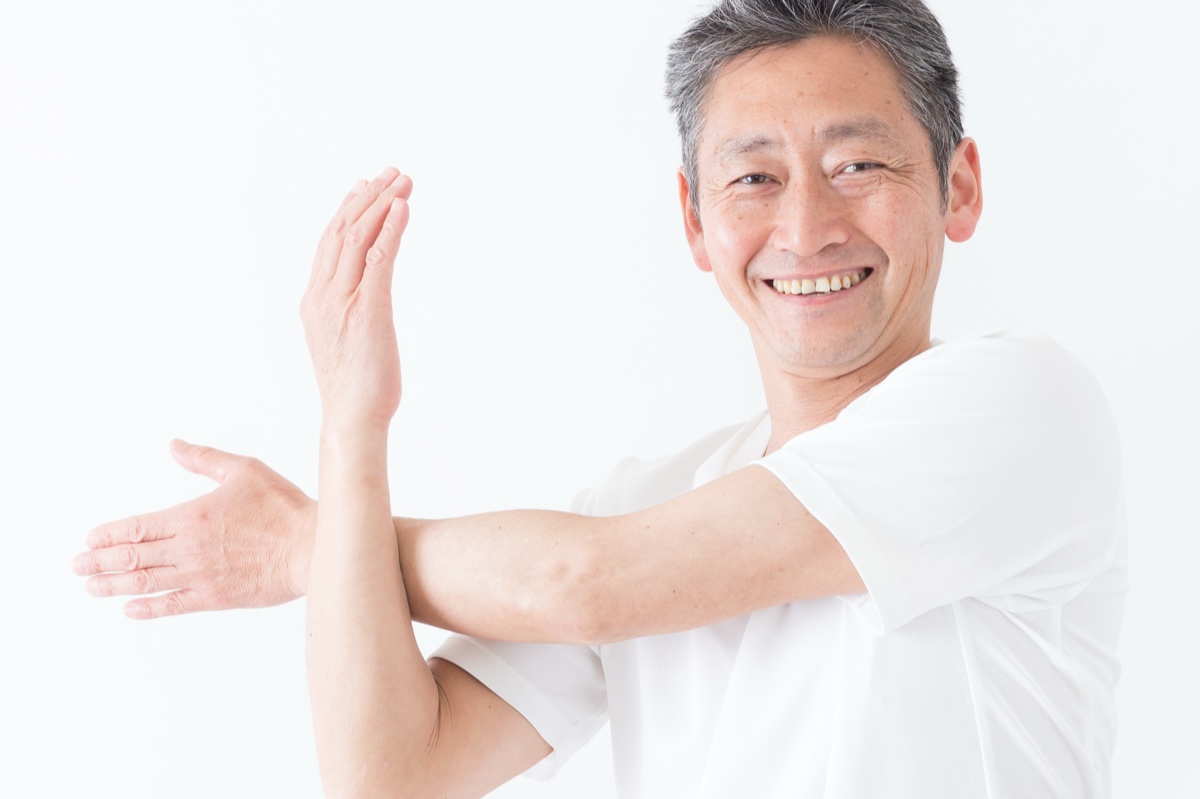 片腕を胸の前に伸ばし反対の腕で引き寄せる男性