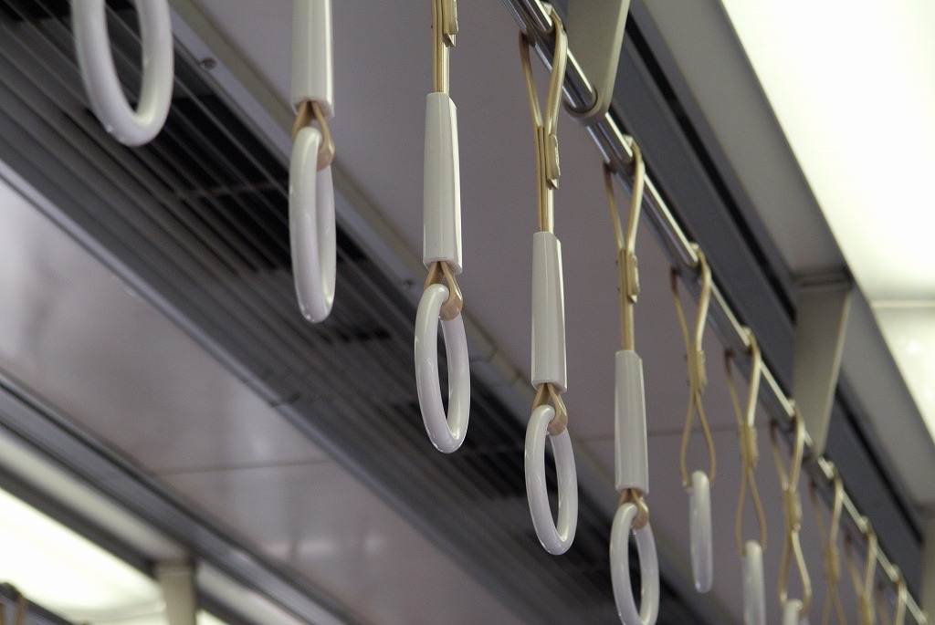 電車の天井の手すりから並んで下がる白いつり革