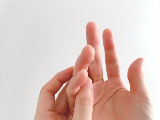 人差し指の関節を、反対の手の指でつまむ手元